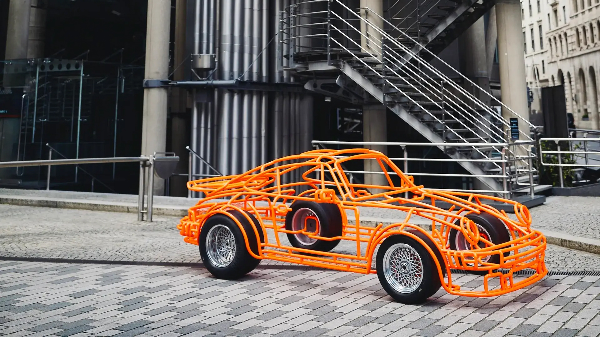 Side-by-side comparison of the steel sculpture and a real Porsche 934 race car.